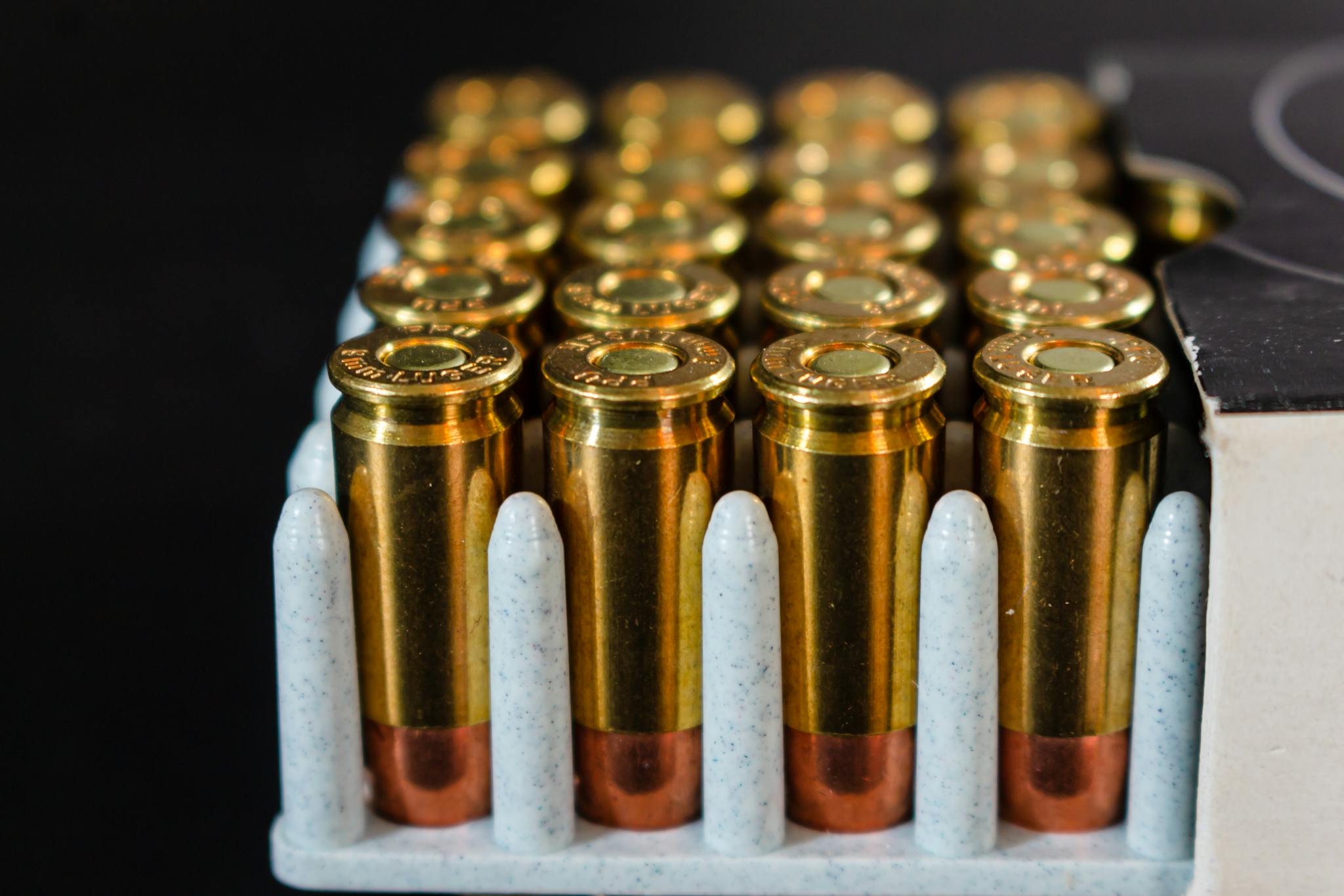Detailed view of ammunition bullets neatly arranged in a box, showcasing brass casings and copper tips.