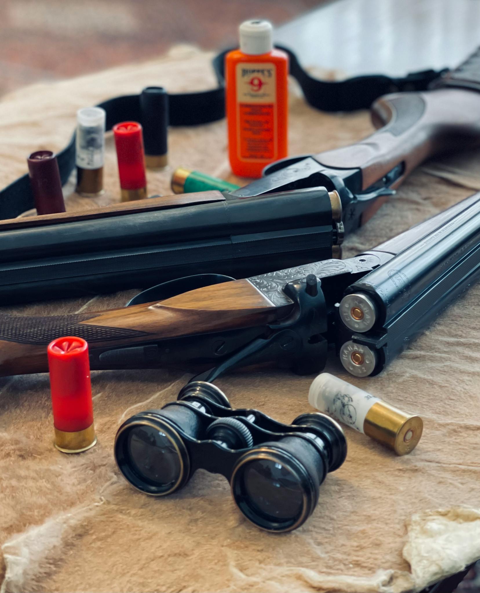 Shotgun with ammunition and binoculars on fur. Ideal for hunting themes.